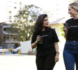 Two women walking outisde holding coffee cups