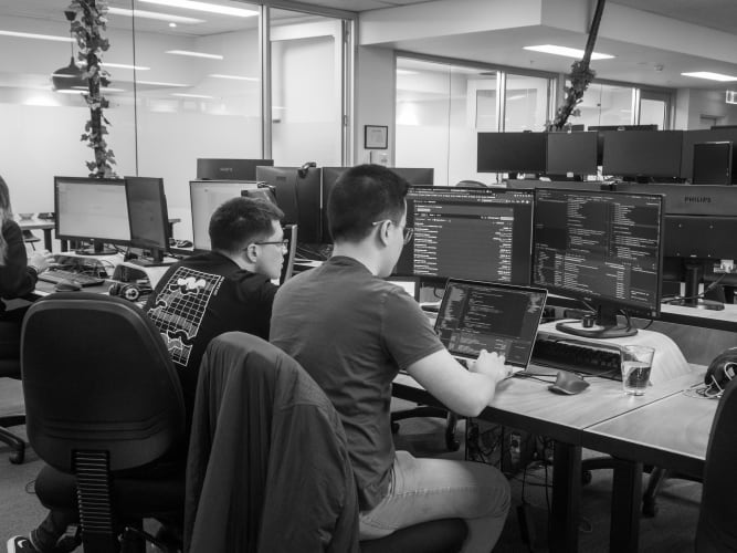 two men sitting next to each other working on computers