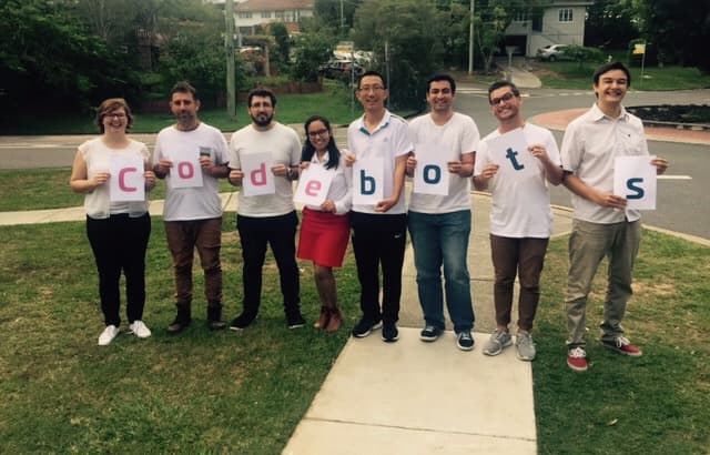 A group of people standing outdoors, holding individual signs spelling ‘Codebots,’ showcasing team collaboration and support for the Codebots platform.