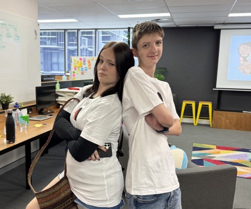 Two students standing back to back, showing off their new workingmouse shirts