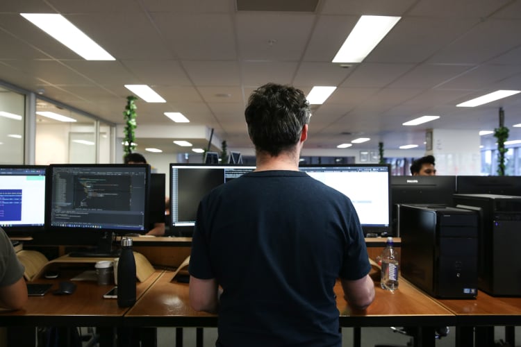 A man with his back to the camera working on a computer