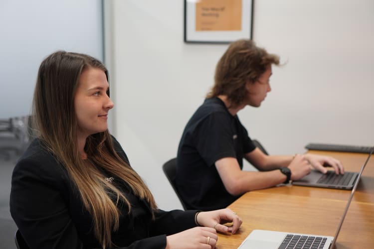 A man and a woman sitting at a table working on laptops