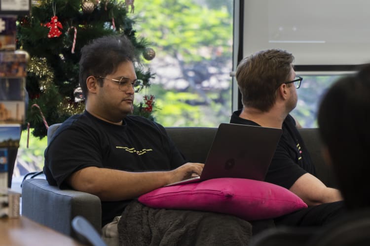 Two men sittingon a sofe. One of the is on a laptop