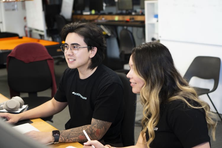 A man and a woman working on a computer together in an office setting