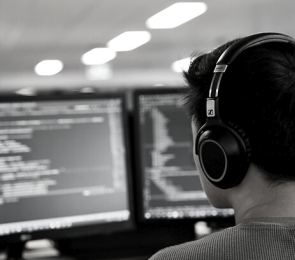 A black and white photo of a man wearing headphones working at a computer